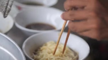 Tavuklu erişte hazırlıyorum. Penjual mie ayam bakso ya da alıcıya tavuklu erişte yapan köfteli tavuklu erişte satıcısı manzarası. Seçici odak. 