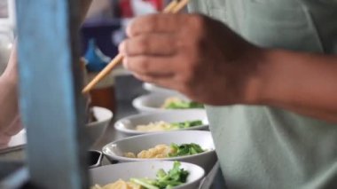 Tavuklu erişte hazırlıyorum. Penjual mie ayam bakso ya da alıcıya tavuklu erişte yapan köfteli tavuklu erişte satıcısı manzarası. Seçici odak. 