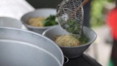 Tavuklu erişte hazırlıyorum. Penjual mie ayam bakso ya da alıcıya tavuklu erişte yapan köfteli tavuklu erişte satıcısı manzarası. Seçici odak. 