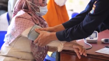 Tarakan, Endonezya-02 10 2023: Endonezyalı bir sağlık görevlisi Tarakan, Endonezya 'da aşı yapmadan önce kan basıncını kontrol ediyordu.