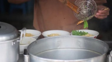Tavuklu erişte hazırlıyorum. Penjual mie ayam bakso ya da alıcıya tavuklu erişte yapan köfteli tavuklu erişte satıcısı manzarası. Seçici odak. 