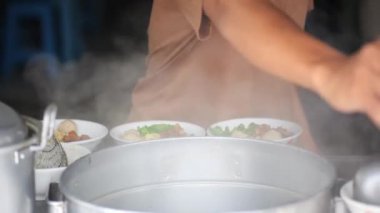 Tavuklu erişte hazırlıyorum. Penjual mie ayam bakso ya da alıcıya tavuklu erişte yapan köfteli tavuklu erişte satıcısı manzarası. Seçici odak. 