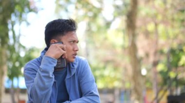 Keyifli genç Endonezyalı günlük tişörtlü adam telefonla konuşuyor ve mobil sohbetin tadını çıkarıyor. İnsanların yaşam tarzı konsepti. Cep telefonuyla konuşuyorum. Asyalı genç adam.