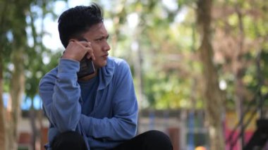 Keyifli genç Endonezyalı günlük tişörtlü adam telefonla konuşuyor ve mobil sohbetin tadını çıkarıyor. İnsanların yaşam tarzı konsepti. Cep telefonuyla konuşuyorum. Asyalı genç adam.