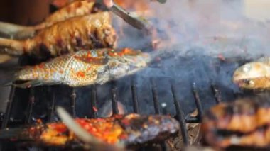 Balık pişirirken yakın çekim. Izgarada marine edilmiş balık pişirme ve kızartma. Kömürün üzerinde ızgara yapılmış deniz balığı. Ikan bakar. Seçici odak.
