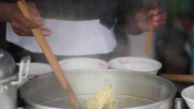 Tavuklu erişte hazırlıyorum. Penjual mie ayam bakso ya da alıcıya tavuklu erişte yapan köfteli tavuklu erişte satıcısı manzarası. Seçici odak. 