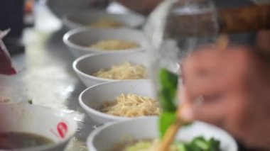 Tavuklu erişte hazırlıyorum. Penjual mie ayam bakso ya da alıcıya tavuklu erişte yapan köfteli tavuklu erişte satıcısı manzarası. Seçici odak. 