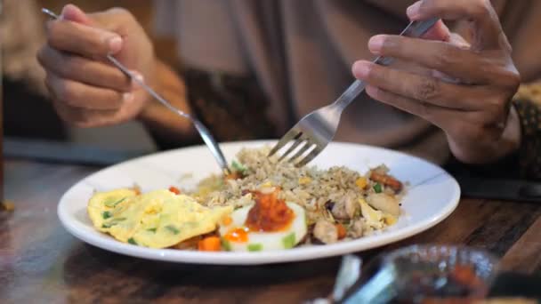 スプーンで炒飯やナシゴレン インドネシア人 を食べ レストランでフォークをかけるインドネシア人女性 — ストック動画