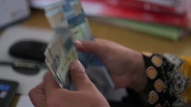 Tarakan, Endonezya .07 20 2023: İşadamı elinde para sayar. İş adamı Rupiah 'ı elinde tutar. Adam kağıt para sayıyor. Seçici odak.