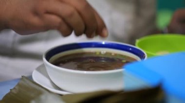 Coto Makassar Geleneksel Et Çorbası içiyorum. Coto Makassar, Güney Sulawesi, Makassar 'dan geleneksel yemek. Biftekle karıştırılmış sığır sakatatından yapılır, özel formüle edilmiş baharatlarla tatlandırılır..