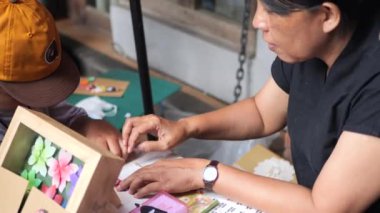 Tarakan, Endonezya 08 04 2023: Endonezyalı bir kadın öğretmen ve kağıt işiyle origami zanaat yapan küçük bir çocuk