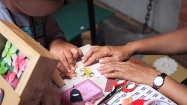 Tarakan, Endonezya 08 04 2023: Endonezyalı bir kadın öğretmen ve kağıt işiyle origami zanaat yapan küçük bir çocuk