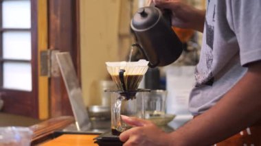 Drip Brew Coffee hazırlayan Endonezyalı bir baristasa. Alternatif kahve demleme metodu, damlatıcı ve kağıt filtresinin üzerine dökülüyor.
