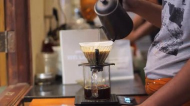 Drip Brew Coffee hazırlayan Endonezyalı bir baristasa. Alternatif kahve demleme metodu, damlatıcı ve kağıt filtresinin üzerine dökülüyor.