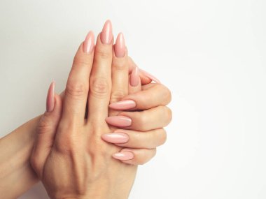 Modayı takip eden genç bir kadın beyaz arka planda pembe manikür yapıyor.