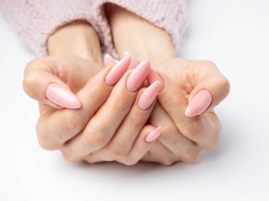 Modayı takip eden genç bir kadın beyaz arka planda pembe manikür yapıyor.