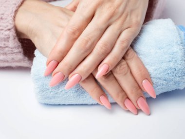 Modayı takip eden genç bir kadın beyaz arka planda pembe manikür yapıyor.