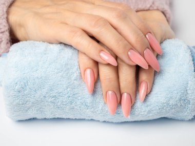 Modayı takip eden genç bir kadın beyaz arka planda pembe manikür yapıyor.
