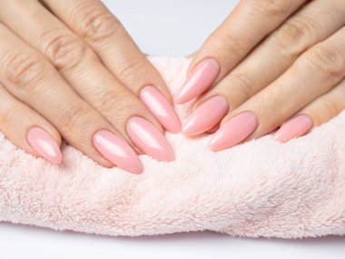 Modayı takip eden genç bir kadın beyaz arka planda pembe manikür yapıyor.