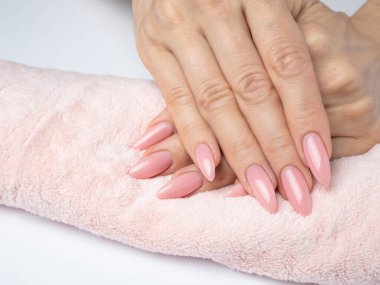 Modayı takip eden genç bir kadın beyaz arka planda pembe manikür yapıyor.