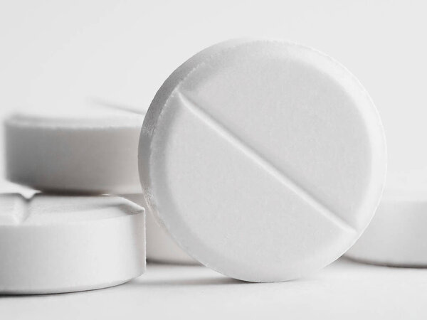 Белые круглые таблетки на белом фоне. Куча маленьких круглых лекарств. Здравоохранение и медицина.