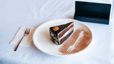 Beyaz bir tabakta beyaz bez masanın üzerinde duran lezzetli çikolatalı pasta. Kafe arka planı. Gıda ve restorasyon konsepti