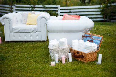 Konuklar için sepetlerde beyaz koltuklar, mumlar ve battaniyeler olan düğün salonu. Parti sırasında doğada rahat bir atmosfer..