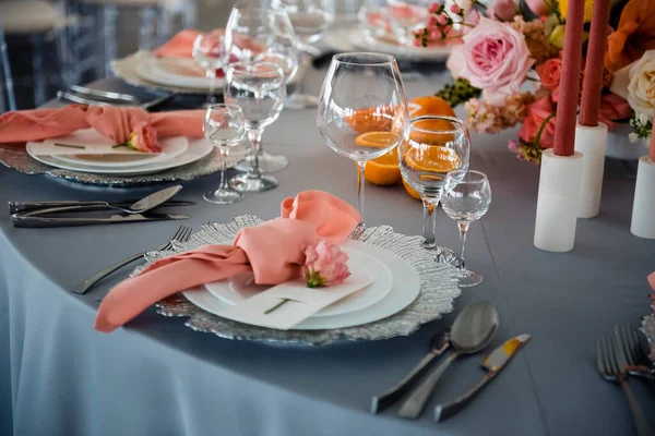奇形怪状的餐桌上有豪华的盘子 眼镜和餐具 配以油腻的色彩组合 婚礼的细节 鲜花和蜡烛作为装饰 — 图库照片