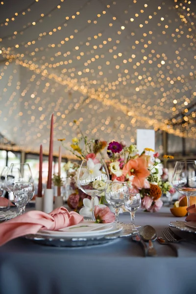 节日餐桌摆设由豪华盘子 陶器和粉红餐巾制成 黄色的花环挂在天花板上 桌上的各种花卉组合 — 图库照片