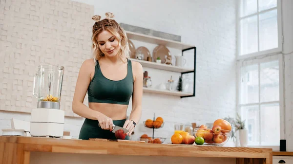 明るいキッチンに立って 新鮮なオレンジジュースを行う緑のスポーツ服の美しいフィットネス女性 健康的な食生活の概念 — ストック写真