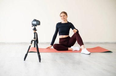 Spor giyim bölümündeki atletik kadın blogcu yoga sınıfında kamera önünde video çekiyor. Spor ve eğlence konsepti. Sağlıklı yaşam tarzı.