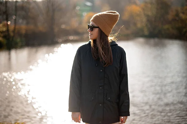 美しい若いリラックスした女性の帽子とコート秋に川で瞑想新鮮な空気を呼吸自然を楽しんで — ストック写真