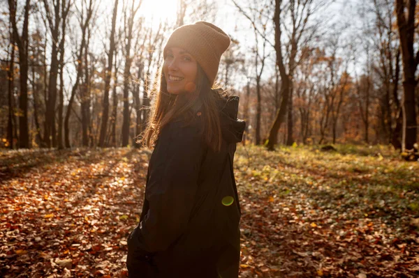 在美丽的秋日里 一个微笑的女人 带着五彩缤纷的落叶 穿过森林 对着相机微笑着 — 图库照片