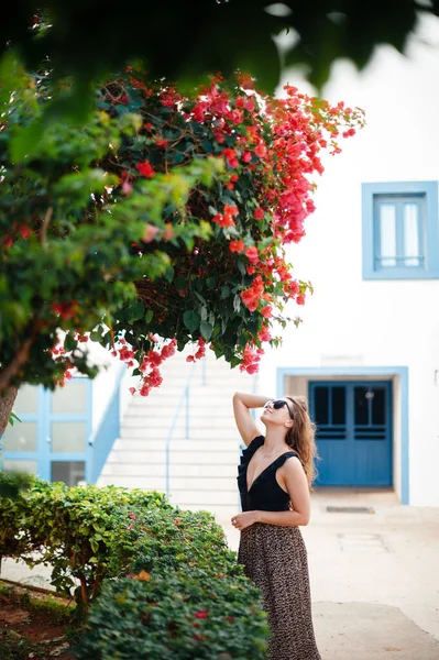 穿着时髦太阳镜和夏装的年轻女子在户外摆姿势 同时在豪华热带度假胜地放松一下 棕榈树和周围的绿色自然 — 图库照片