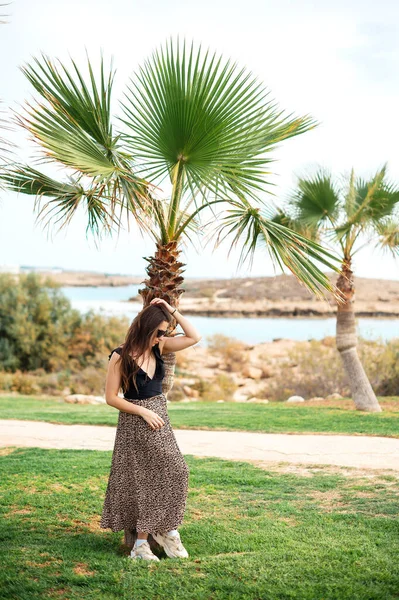 全长肖像美丽的高加索女人穿着时髦的衣服 戴着太阳镜 站在美丽的酒店附近的棕榈树 暑假的乐趣 — 图库照片