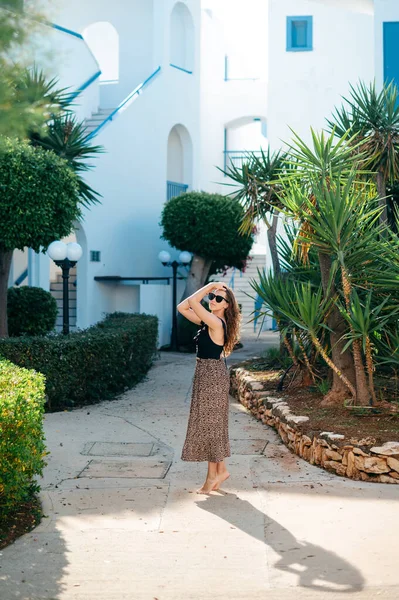 穿着夏装 戴着太阳镜的可敬的年轻女子 站在现代酒店的地盘上 周围长着棕榈树和绿叶 暑假期间的放松和享受 — 图库照片