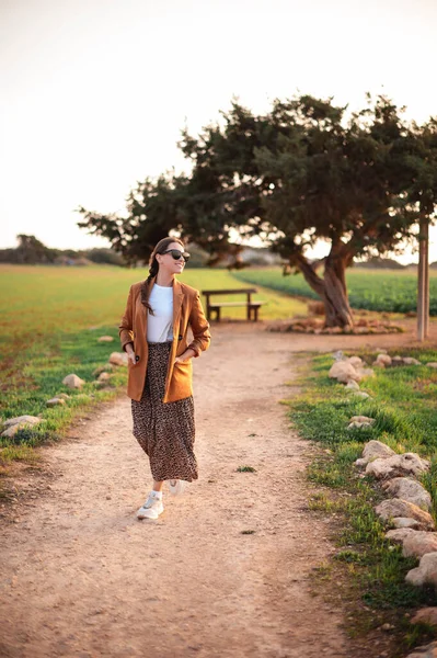 在Ayia Napa 一个身穿时髦衣服 戴着太阳镜的黑发女人站在恋人的树旁笑着 访问塞浦路斯热门地区的女性游客 — 图库照片