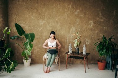 Genç, sıska bir kadın ahşap sandalyede oturuyor ve geniş çatı katında tank davulunda çalıyor. Sportif kıyafetler giymiş, ruhani müzik enstrümanı üzerinde çalışan ve harika melodilerden hoşlanan hoş bir bayan..