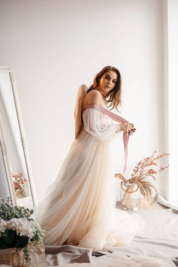 Gelinlik giymiş şapkalı güzel gelin. Stüdyoda poz veren mutlu yeni evli kadın. Düğün makyajlı ve saç stili gelin. Düğün günü ve evlilik kavramı 