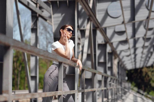 一位严肃的女商人戴着太阳镜站在桥上 在休息的时候一边看一边放松 — 图库照片