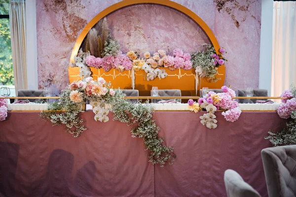 宴会厅的节庆桌上装饰着美丽的花卉作曲 金色拱门 新娘和新郎的座位后面开满了花 结婚的概念 — 图库照片