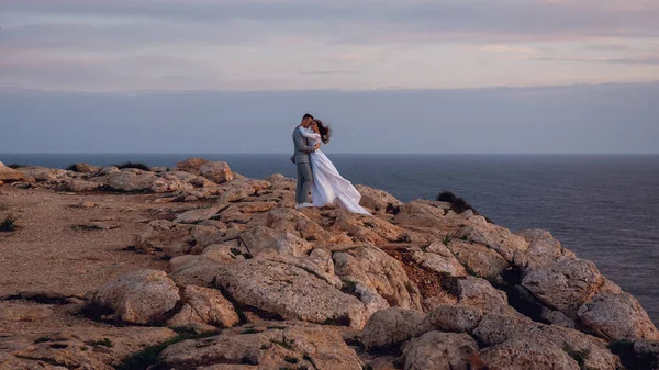 Молодая Свадебная Пара Невеста Жених Гуляющие Обнимающиеся Каменистом Пляже Моря — стоковое фото