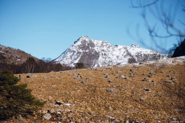 Norveç 'te karlı zirveleri olan dağların ve tepelerin muhteşem ilkbahar manzarası. Güneşli bir günde mavi gökyüzü