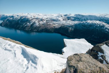 Dağlı, karlı tepeli, kayalık kıyıları olan güzel bir göl manzarası. Minber Rock 'ın en üst görüntüsü, Preikestolen. Lysefjord, Norveç