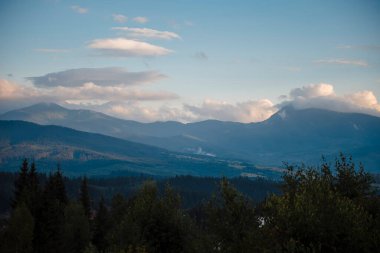Mavi gökyüzü ve ışık bulutlarıyla yeşil görkemli dağların muhteşem manzarası. Doğa duvar kâğıdı ve arka plan. Güzel manzara.
