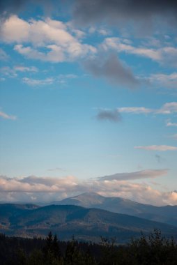 Gökyüzündeki ışık bulutları arasında yüksek görkemli dağ zirvelerinin en üst görüntüsü. Doğal manzara ve vahşi yaşam konsepti. Güzel manzara.