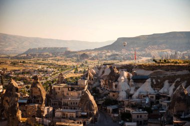 Kapadokya 'daki eski taş evler ve mağaralarla Türk kasabasının resimli görüntüsü. Yaz güneşi etrafımızda. Hava balonları olan ünlü bir yer..