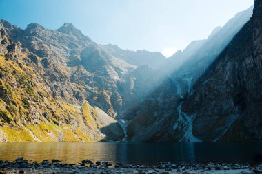 Morskie Oko Gölü yakınlarındaki kayalık Tatra dağları üzerinde güneş ışığı olan sabah gökyüzü. Bahar havasında cilalı doğanın inanılmaz manzarası. Rahatlama ve huzur kavramı..
