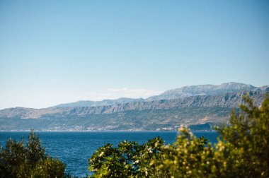 Brac adasının kıyısında panoramik manzaralı yeşil ağaç tepeleri. Güzel, berrak Adriyatik denizi ve yüksek kayalık dağların büyüleyici manzarası. Sakinlik atmosferi.