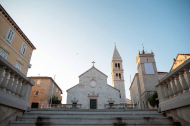 Hırvatistan 'ın Supetar kentindeki temiz gökyüzünün arka planına sahip antik kilisenin alt manzarası. Şehrin atmosferini tamamlayan estetik tapınak mimarisi ve yakınındaki diğer binalarla birlikte..